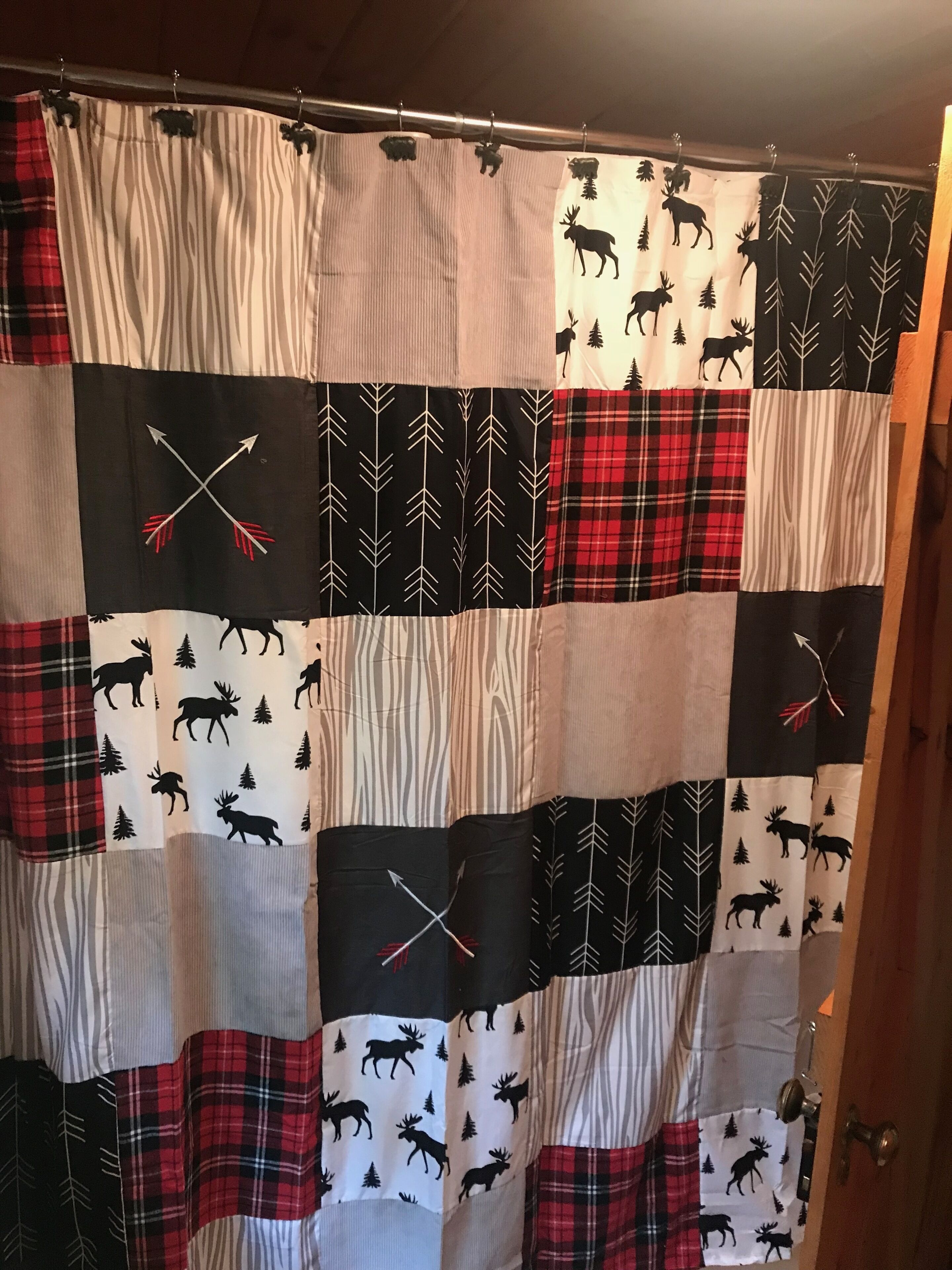 A patchwork curtain with a moose and arrow pattern, likely in a home or cabin setting.