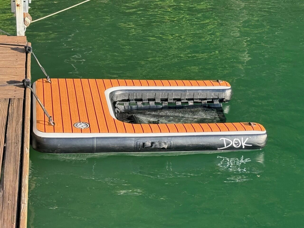 A floating dock with a wooden platform and a metal structure with a name 'DOK' painted on it.