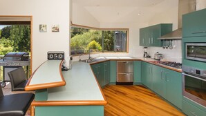A modern kitchen with teal cabinets, a wooden countertop, and a built-in grill area.