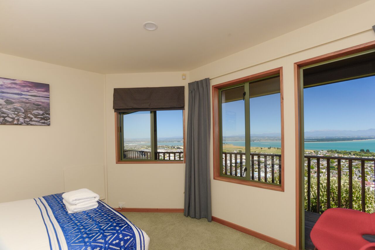 Een hotelkamer met een bed, uitzicht op een meer en een balkon met een hekwerk.