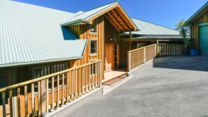 A wooden building with a metal roof, a wooden porch, and a blue trash bin.