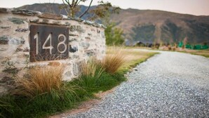 A stone wall with the number 148, a gravel path, and a mountainous backdrop. - Up in the mountains!!! Luxury self contained unit. (Arrowtown)