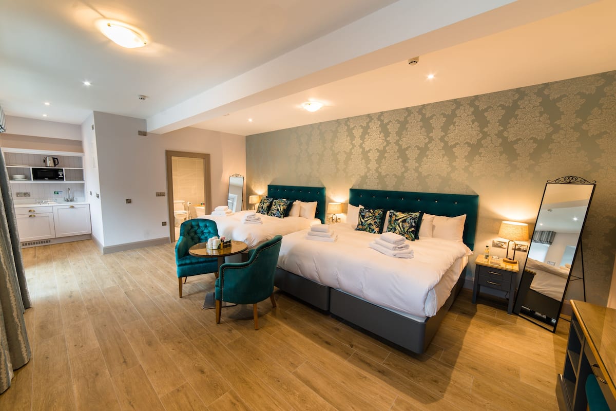 A hotel room with a large bed, two bedside tables, a chair, a desk, and a mirror.