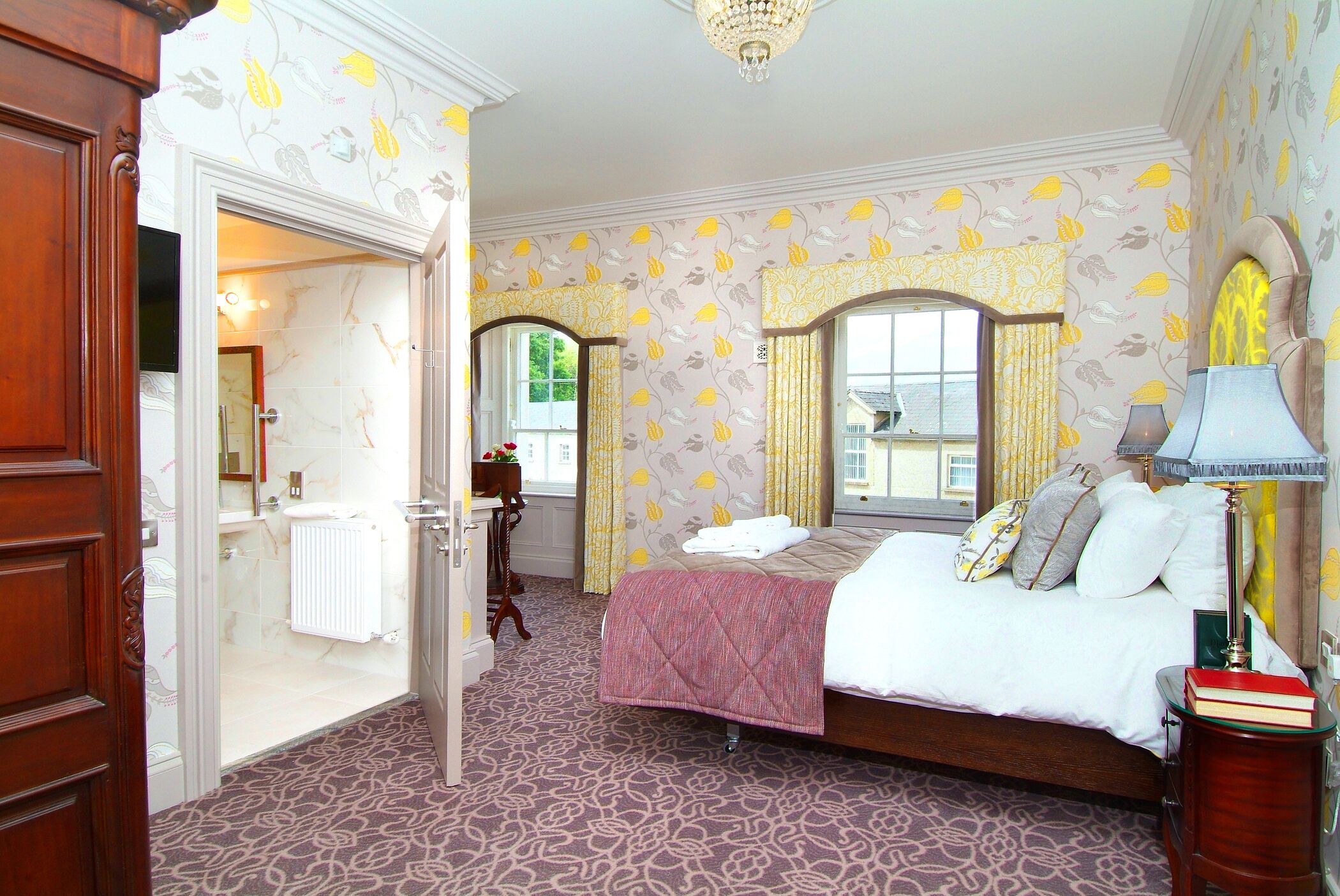 A bedroom with a bed, a bedside table, a lamp, and a window with curtains.