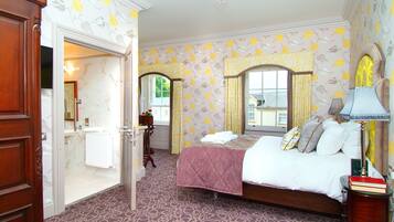 A bedroom with a bed, a bedside table, a lamp, and a window with curtains.