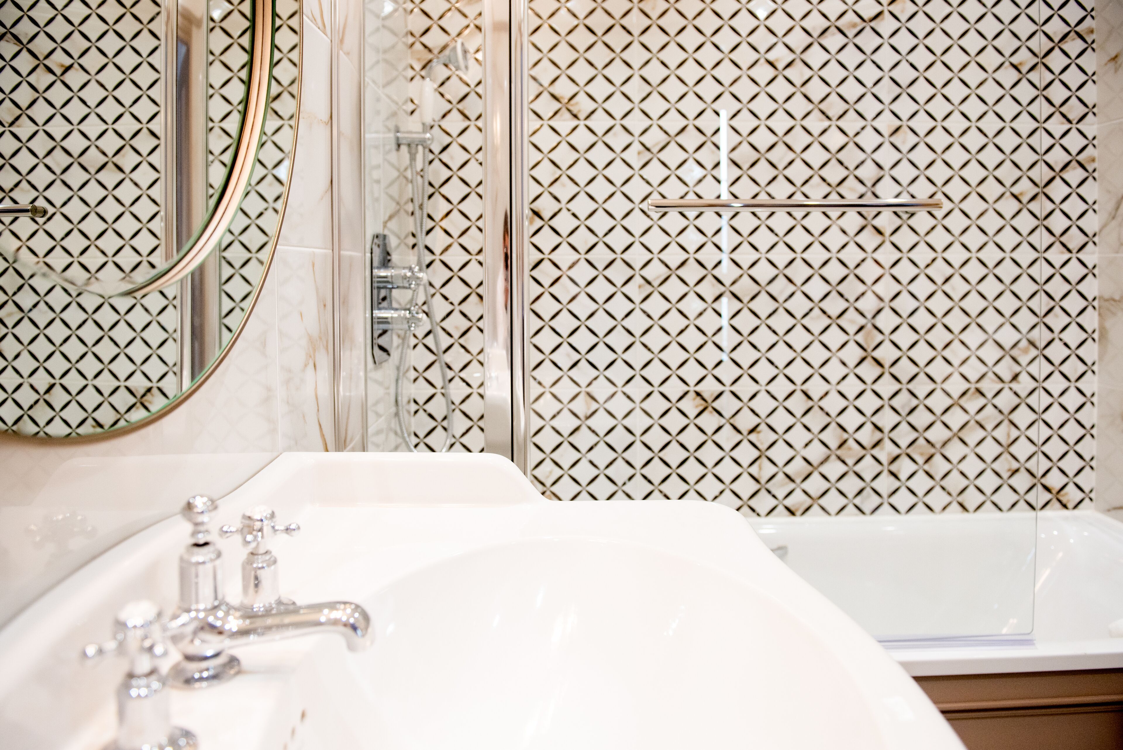 A bathroom with a sink, mirror, and shower.