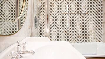 A bathroom with a sink, mirror, and shower.