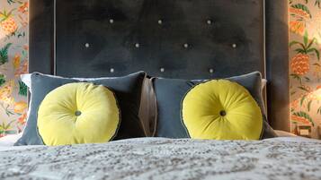 Un letto con testiera imbottita, due cuscini con motivo giallo e copripiumino decorato.