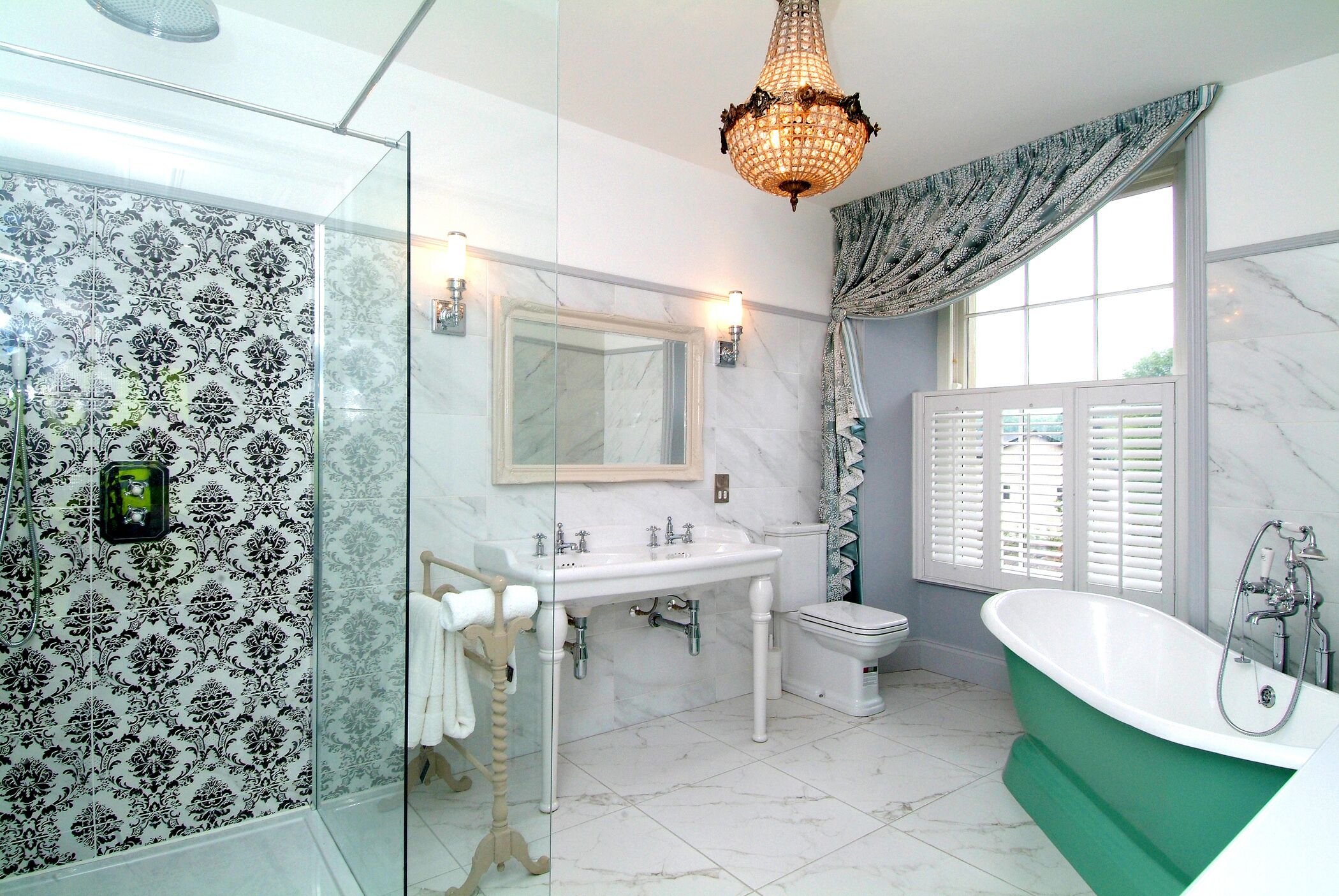 Un baño con cabina de ducha de vidrio, un lavamanos blanco con espejo, un inodoro y una bañera independiente verde.