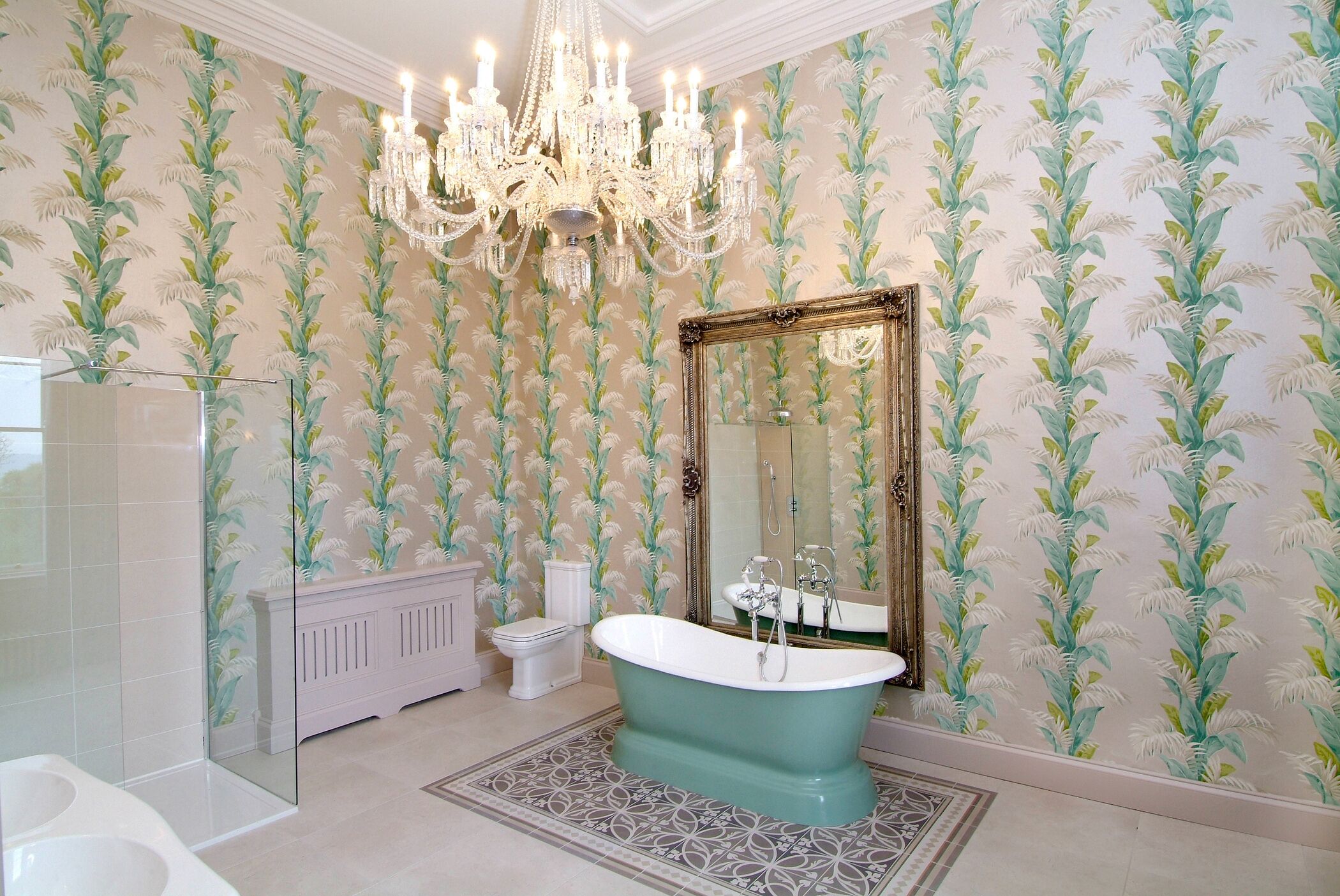A bathroom with a freestanding bathtub, a large mirror, and a chandelier.