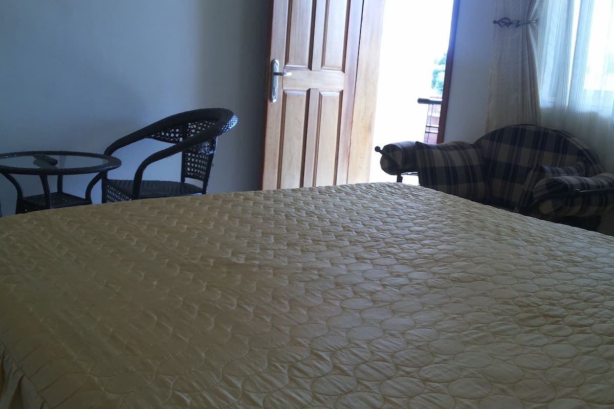 A bed with a quilted cover, a wooden door, a chair, and a table.