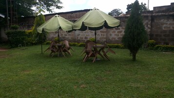 Un patio con dos sombrillas verdes, una mesa y cuatro sillas.