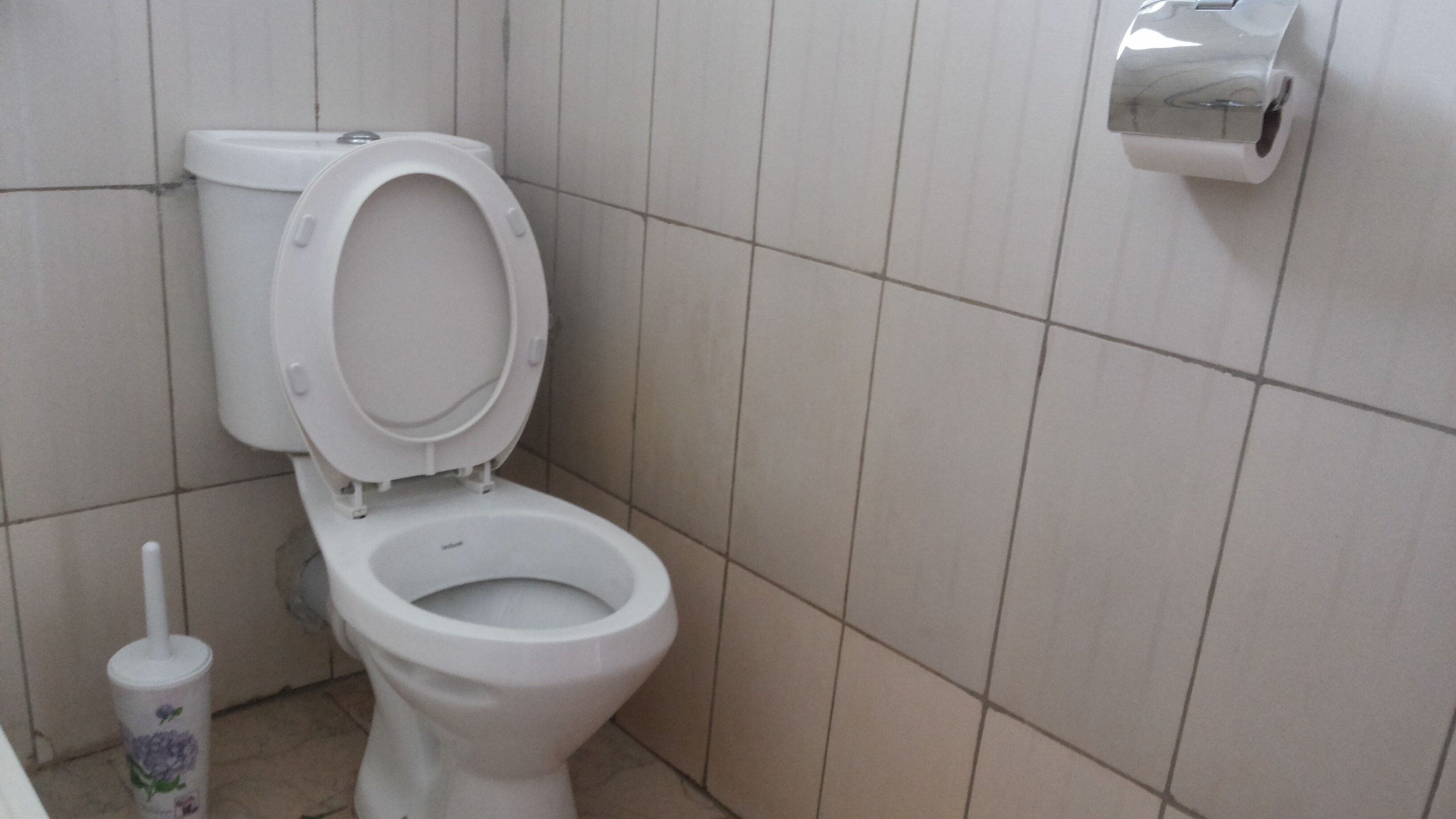 A white toilet with a closed seat in a bathroom with white tiled walls.