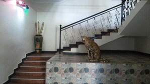 Una estatua de leopardo sobre una escalera con baldosas y una barandilla metálica.