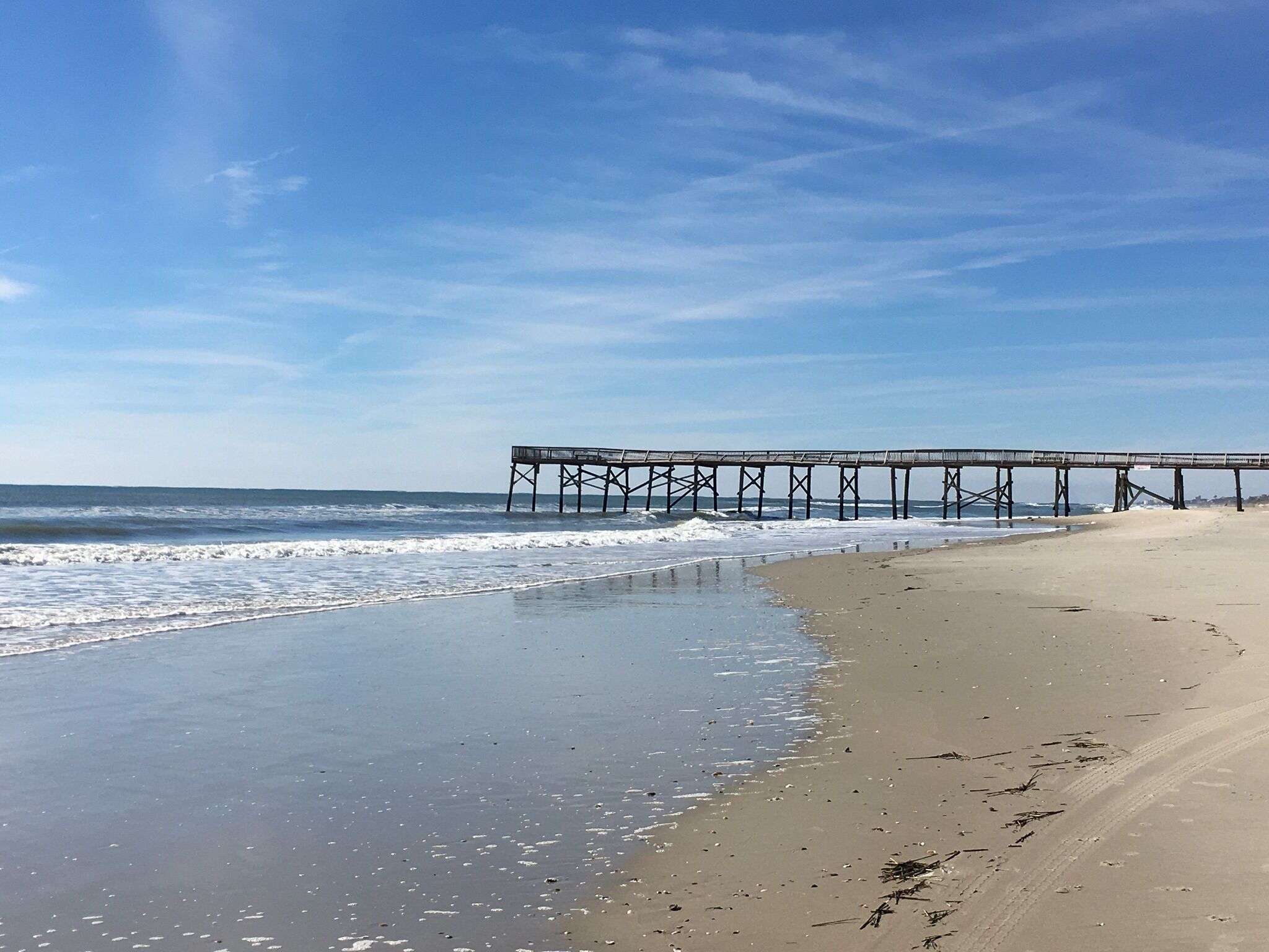 A beach with a pier extending into the ocean.