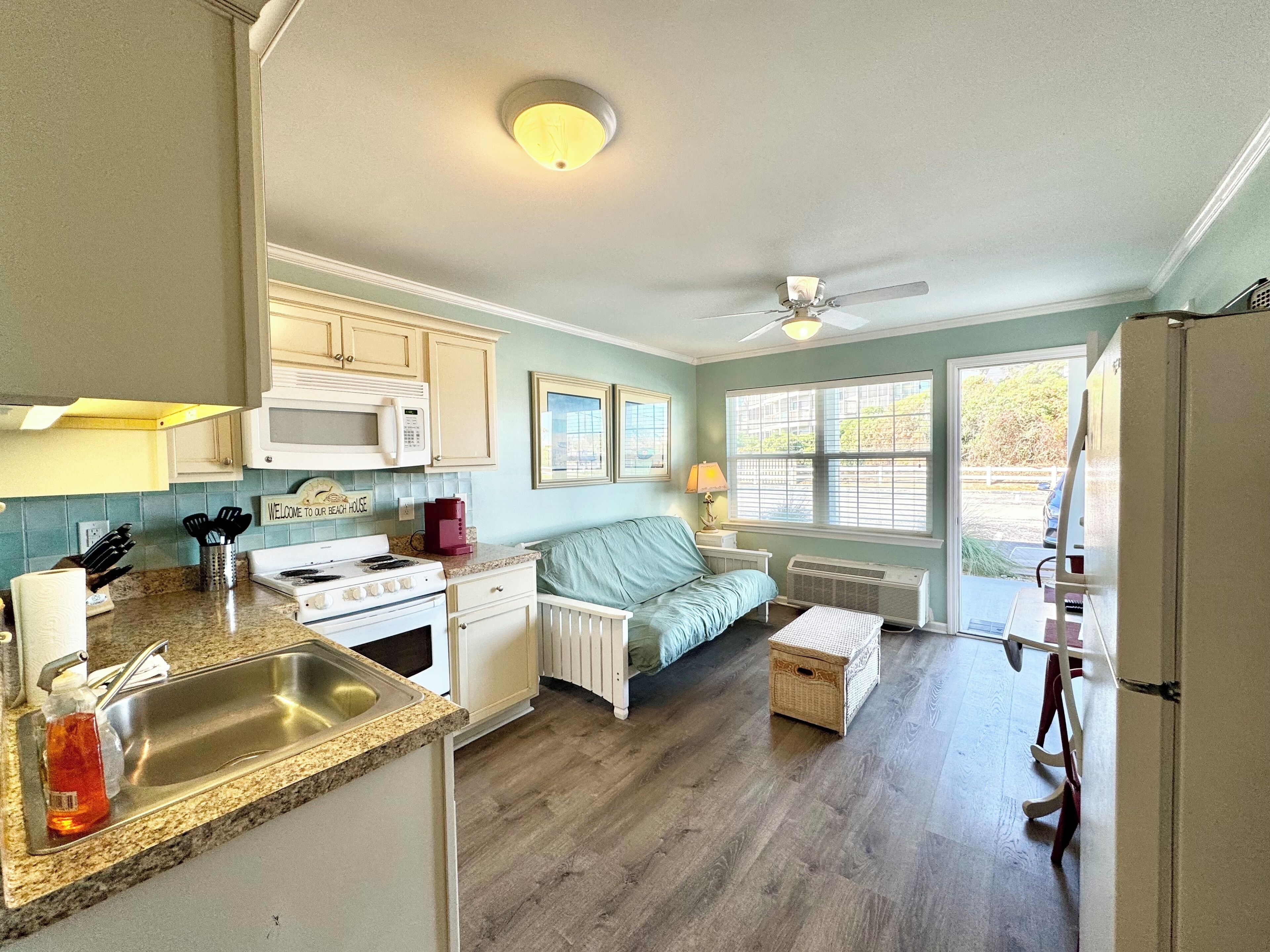 A kitchen with a microwave, stove, sink, and a dining area with a table and chairs.
