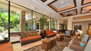 Un hall d’entrée spacieux, doté d’un grand espace salon, d’une table basse et offrant une vue sur le jardin extérieur grâce à de grandes portes vitrées.