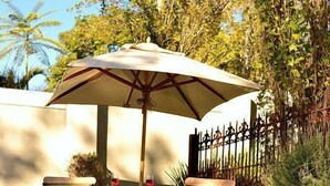 A poolside area with lounge chairs, an umbrella, and a reflection in the water. -  Old Oak Manor (Riebeek Kasteel)