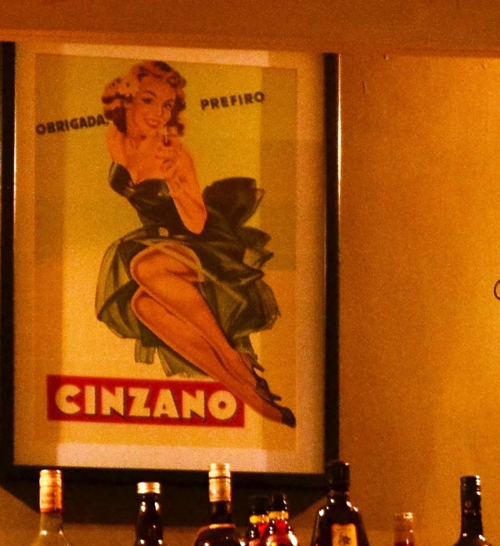 En ældre plakat med en kvinde og ordet "CINZANO" på en væg.