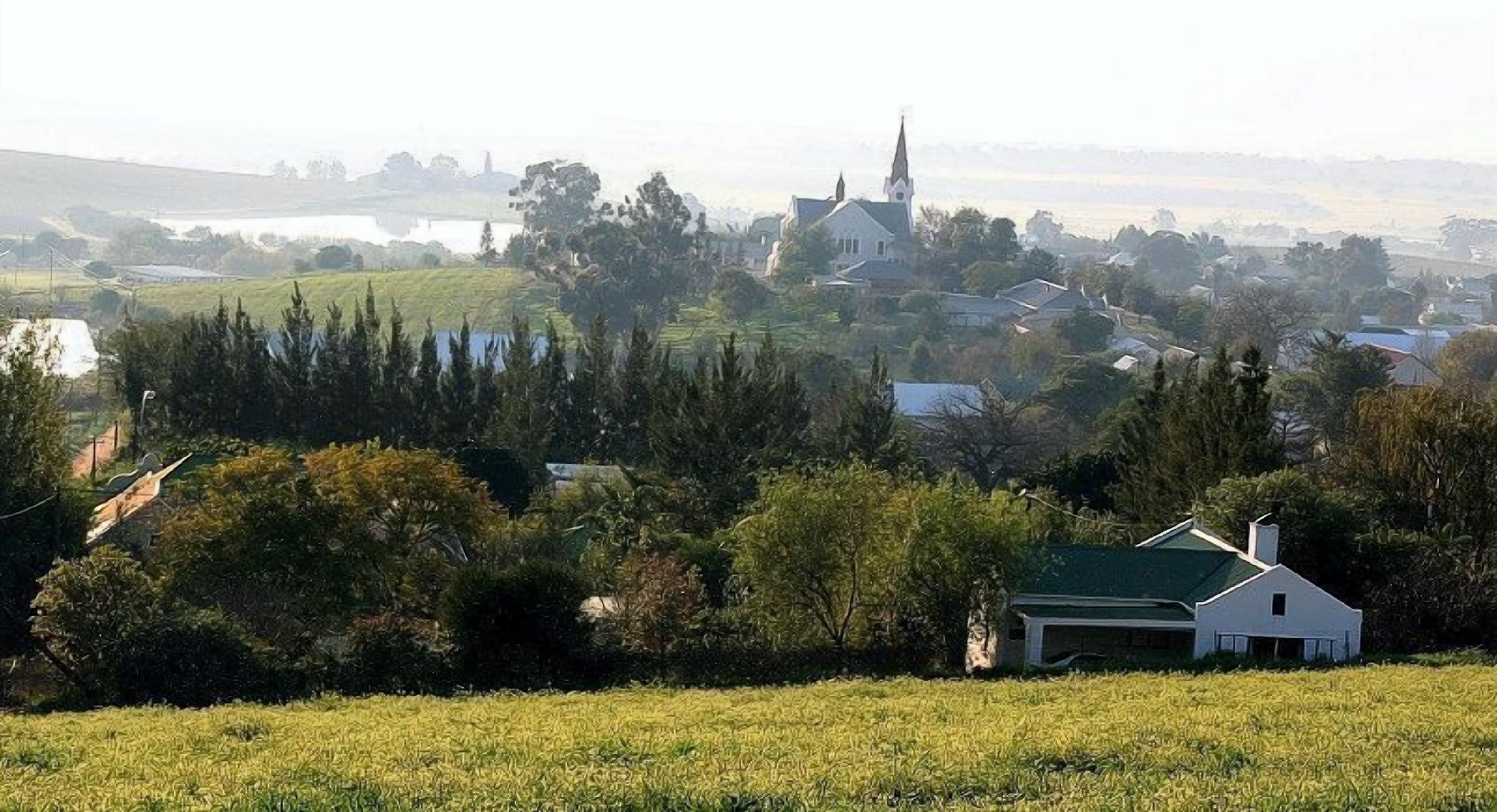 Ett lantligt landskap med en kyrka, hus och ett fält.