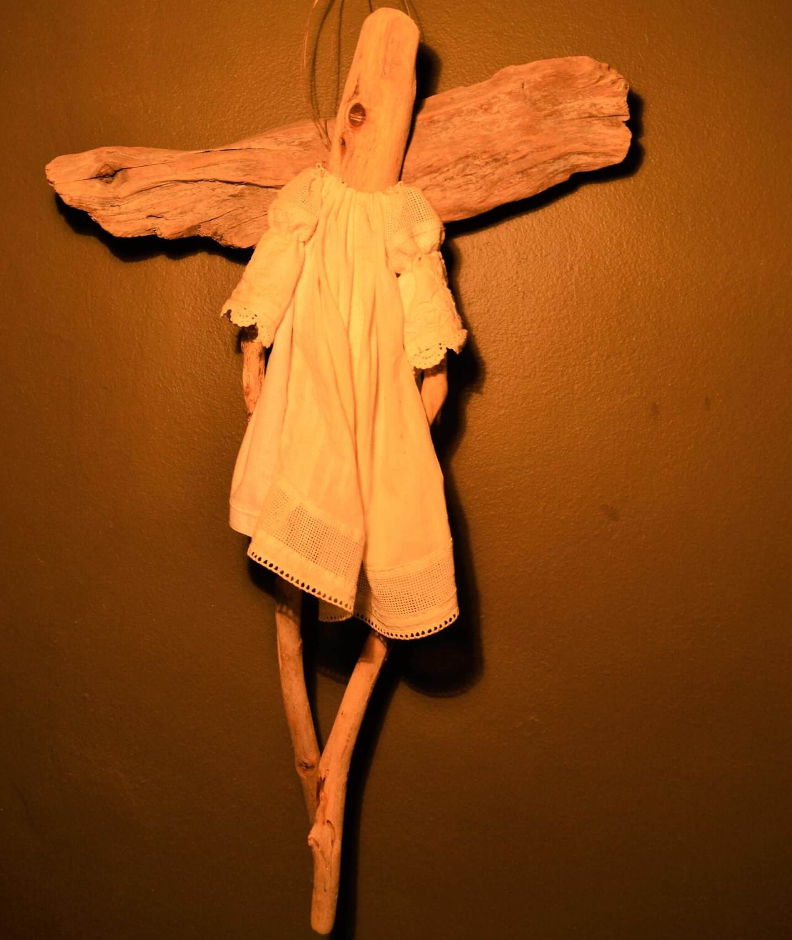 Una figura de madera con alas y vestido, colocada en una pared.