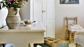 A room with a white table, a vase with pink flowers, a cup, and a chair with a white towel. -  Old Oak Manor (Riebeek Kasteel)