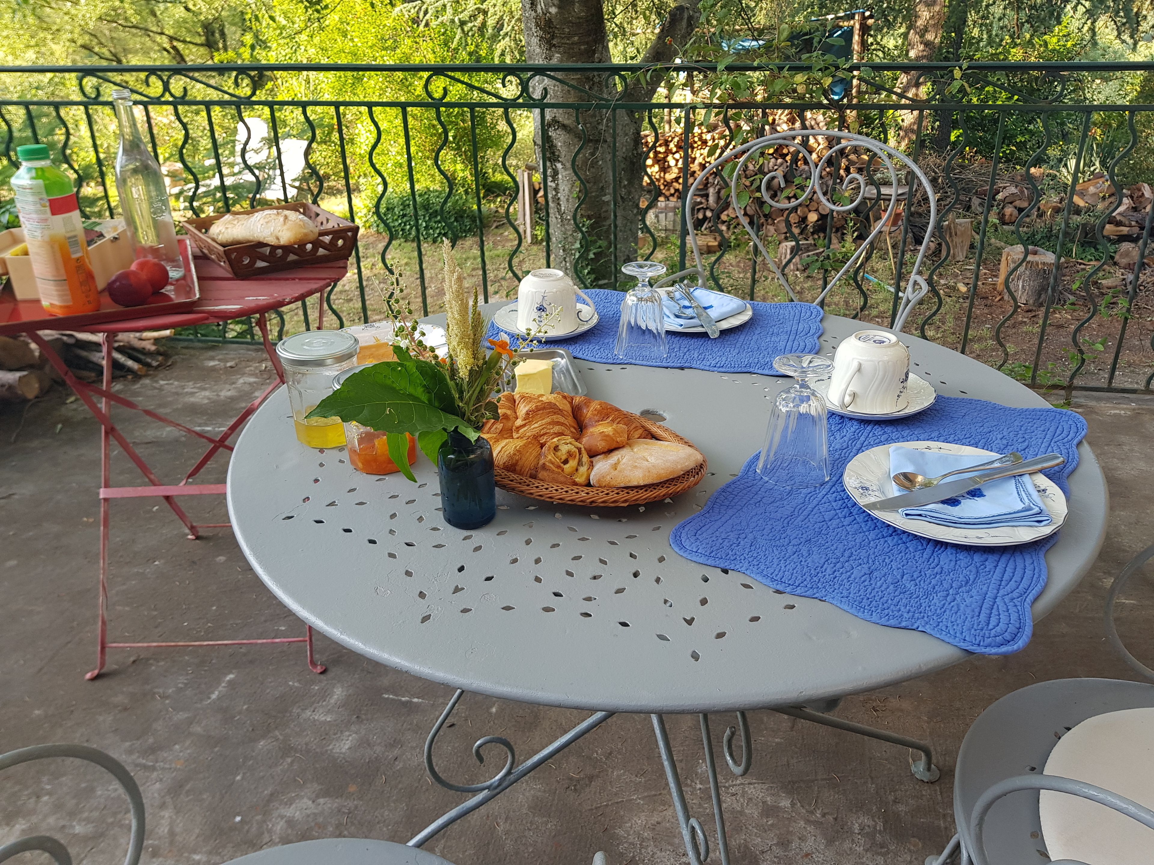 An outdoor dining setup with a table, chairs, and a variety of food and drink items.