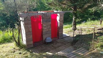 Une structure en bois avec des portes rouges, une petite table et un banc.