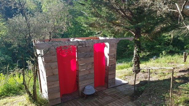 A wooden structure with red doors, a small table, and a bench. - Mas des Ballats (Saint-Bauzille-de-Putois)