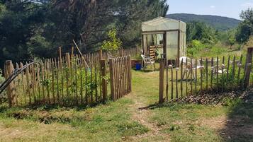 A rustic wooden fence enclosing a garden area with a small shed and outdoor seating.