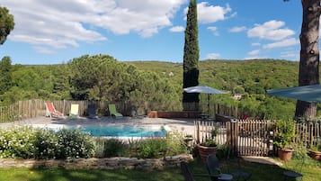 Una piscina al aire libre, sombrillas, sillones reclinables de piscina