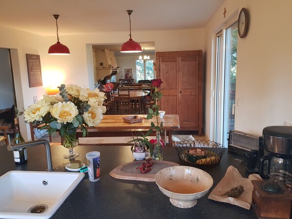 A kitchen with a sink, countertop, and a dining area with a table and chairs. - Mas des Ballats (Saint-Bauzille-de-Putois)