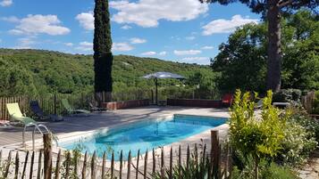 Una piscina al aire libre, sombrillas, sillones reclinables de piscina