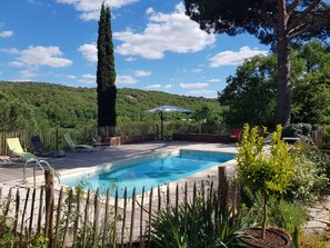 Een buitenzwembad, parasols bij het zwembad en ligstoelen
