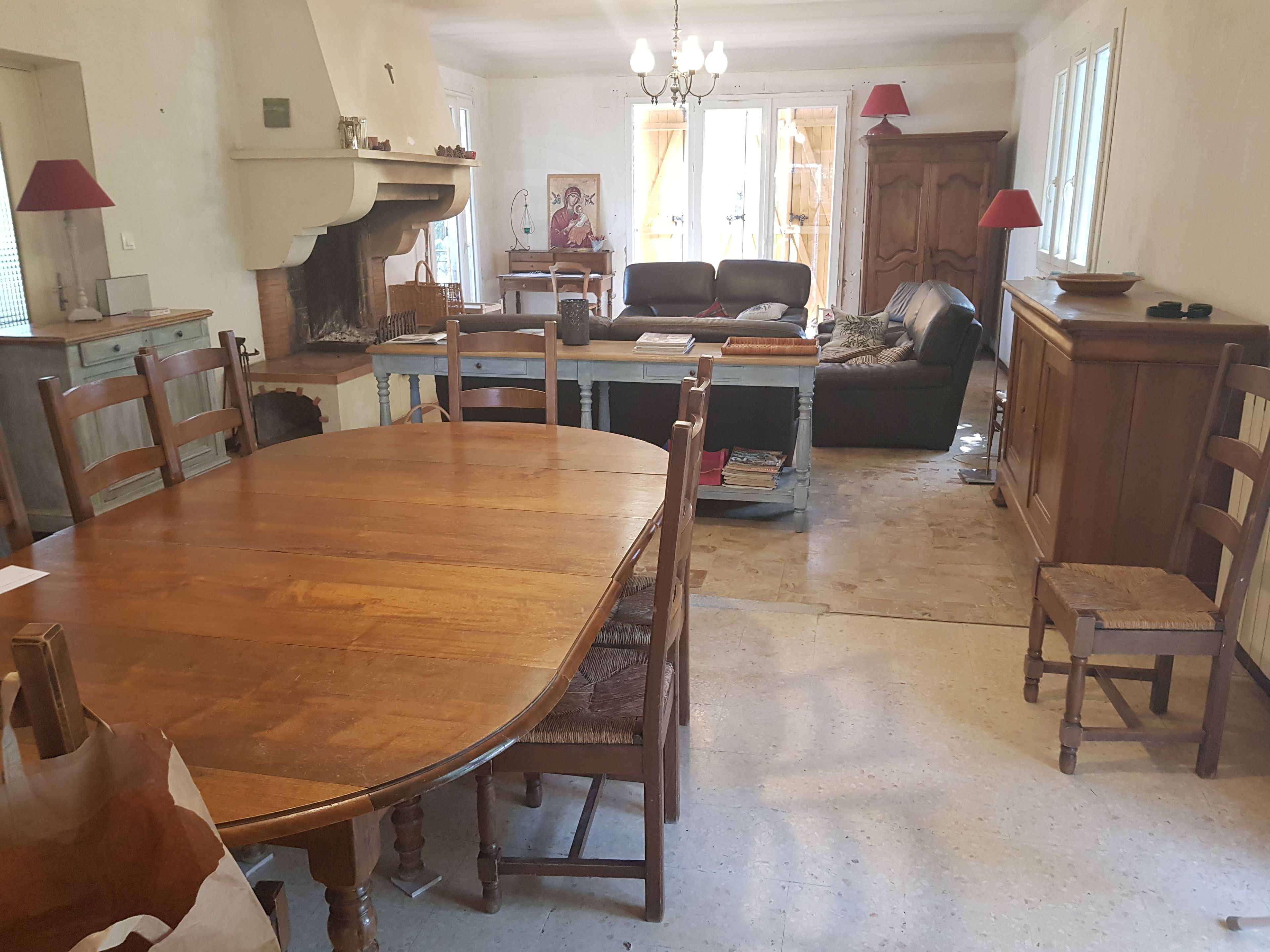 A spacious dining area with a large wooden table and chairs, a sofa, and a cabinet.