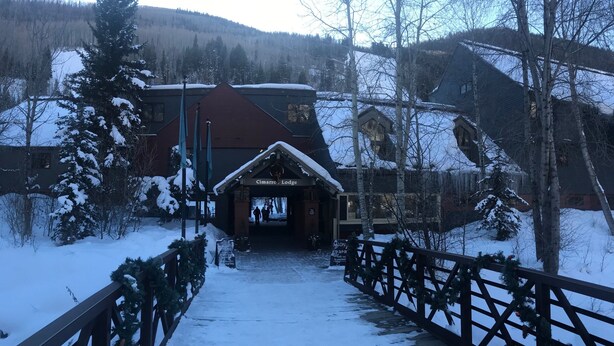 Eingang eines Chalets mit einer Holzdielen-Terrasse und verschneiter Umgebung.