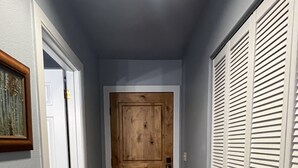 Ein Flur mit Holztür, weißen Schranktüren und einem gemusterten Teppich.