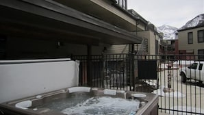 Ein Whirlpool vor einem Gebäude mit einem Metallzaun, einem geparkten Auto und einem Berg im Hintergrund.
