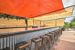 Relax with a drink at the outdoor bar, featuring a long counter and comfortable stools.
