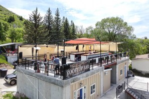 Eine Dachterrasse mit einem Schild, auf dem 'ROOFTOP BAR' steht, und einer Einladung, mitzumachen.