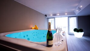 Een moderne binnenzwembadruimte met een jacuzzi, een fles champagne en twee glazen.