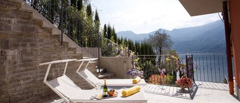 A balcony with a white table, a bottle, and a rolled towel.