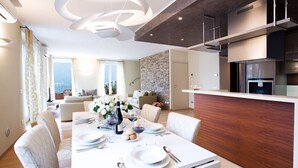Een moderne eetruimte met een witte tafel gedekt voor vier personen, een keuken met een houten aanrecht en een stenen muur.