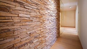 Een gang met een stenen muur en houten vloer.