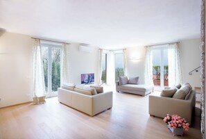Relax in this stylish living room with a sofa, flat-screen TV, and sliding glass door leading to a balcony.