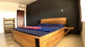 Una cama de madera con cabecera oscura en una habitación con suelo de baldosas y pared oscura.