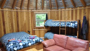 A wooden room with bunk beds, a leather couch, and a window.