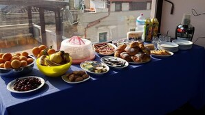 Een tafel met diverse gerechten en een taart, voor een raam met uitzicht op een gebouw en een straat.