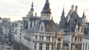 Incrocio cittadino con edifici storici, una linea tramviaria e un attraversamento pedonale.
