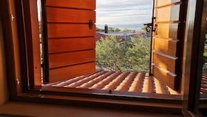 Eine Holztür führt zu einem Balkon mit Blick auf Gebäude und Bäume.